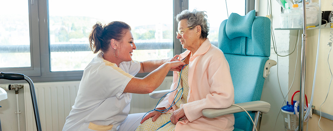 Une aide-soignante s'occupe d'une patiente âgée en neurologie vasculaire.