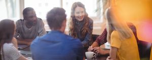 Un groupe de personnes sont attablées et discutent autour d'un café.