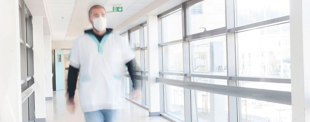 Un personnel avec un masque avance dans un couloir pendant l'épidémie de Covid-19
