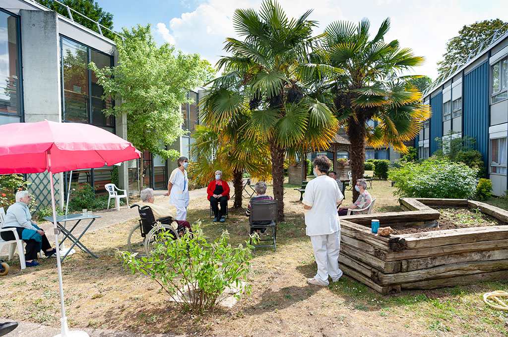 Des soignants et des résidents se trouvent dans le jardin de l'EHPAD Saint-Julien.