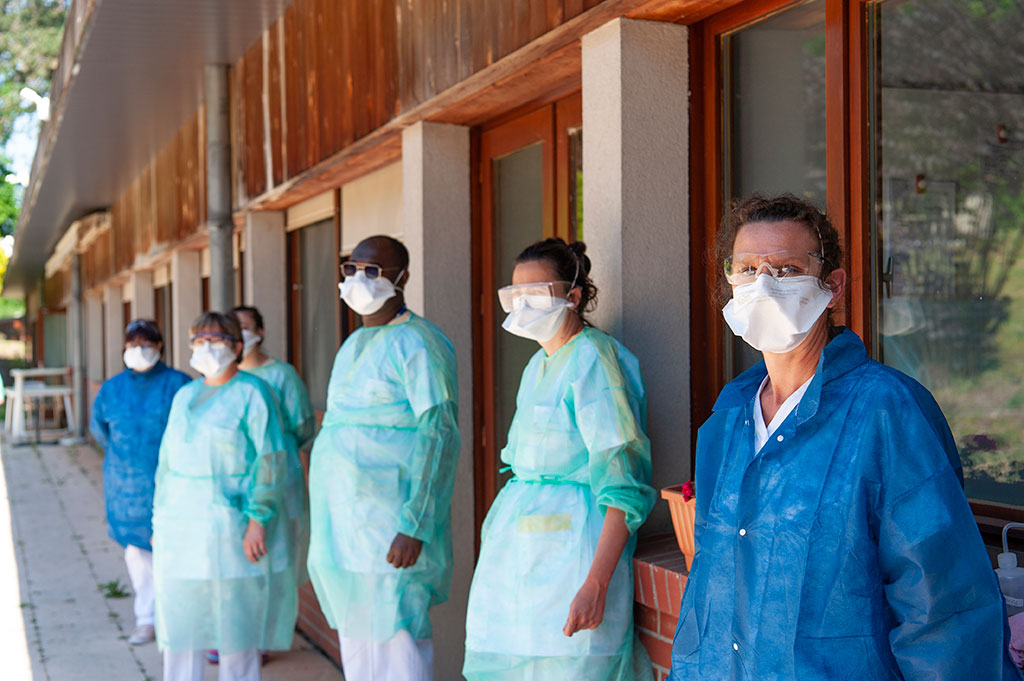 Des soignants en tenues de protection Covid-19 sont alignés face à un bâtiment à l'hôpital de Oissel.