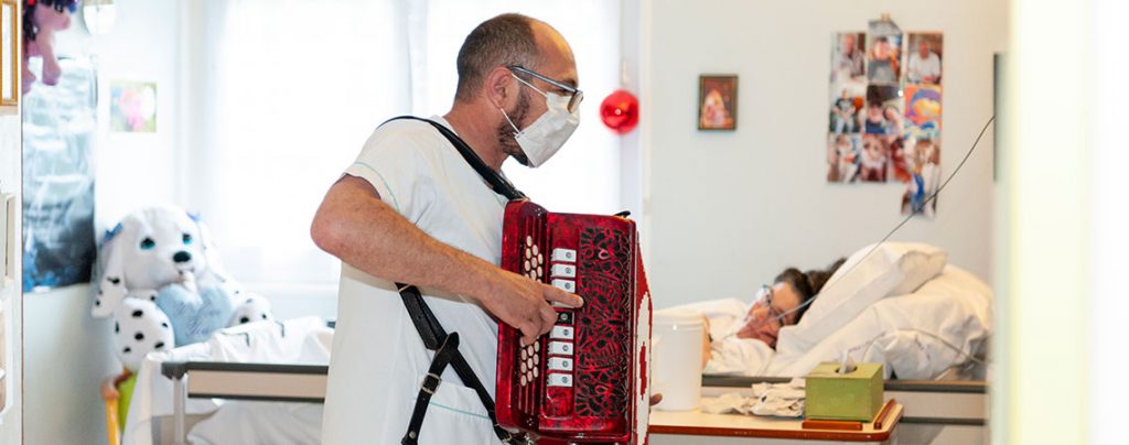 Un animateur joue de l’accordéon pour une résidente de l'hôpital Boucicaut pendant l'épidémie de Covid-19.