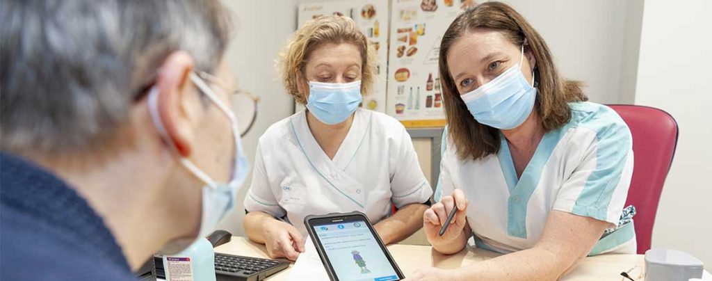 Des soignants s'entretiennent avec une patiente avec l'aide d'une tablette