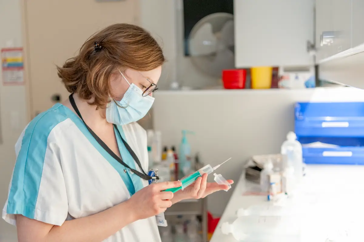 Infirmière manipulant une seringue en salle de soins des maladies infectieuses